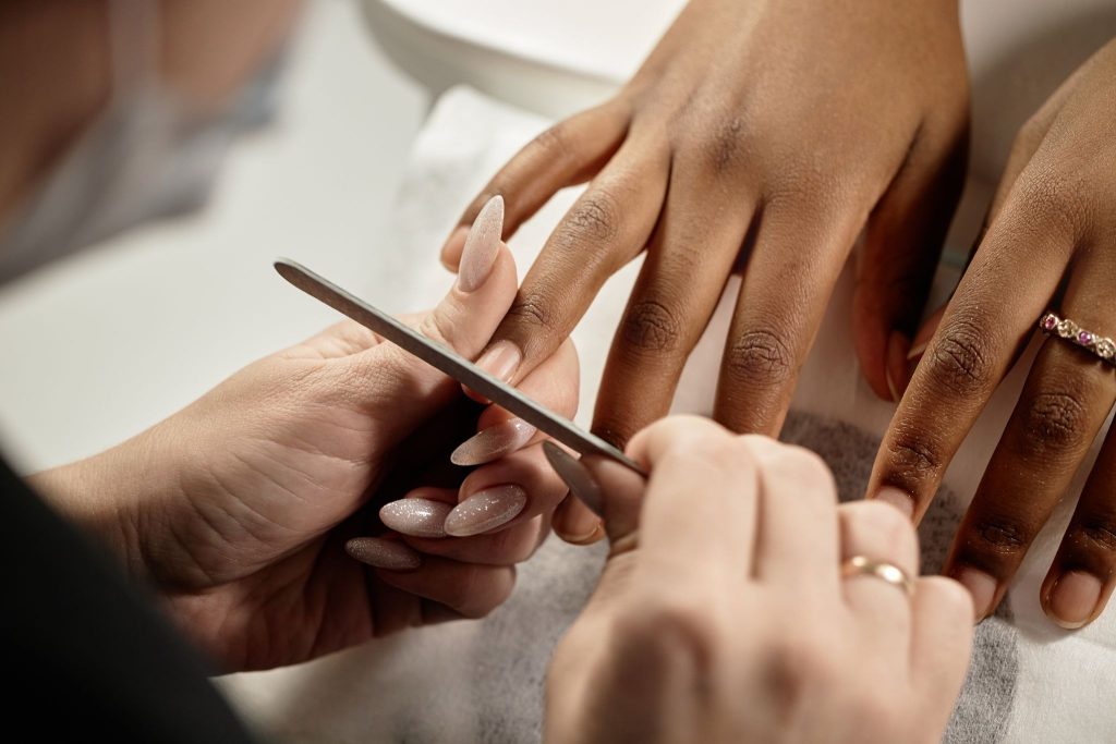 Nail care specialist filing and shaping a client's nails during a salon manicure